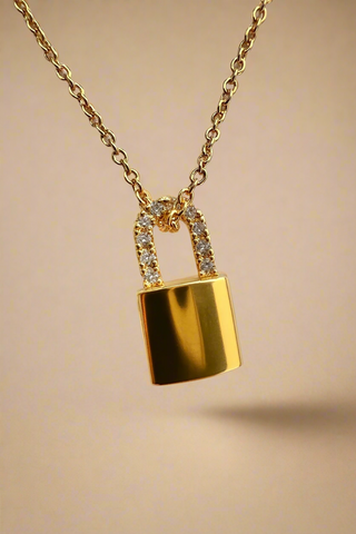 Gold lock-shaped pendant necklace on a light gray background