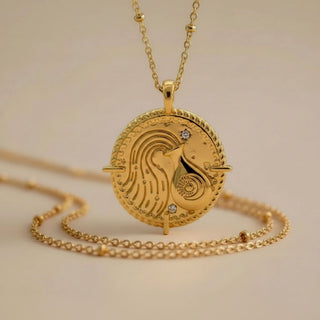 aquarius zodiac necklace in gold hanging in a studio background