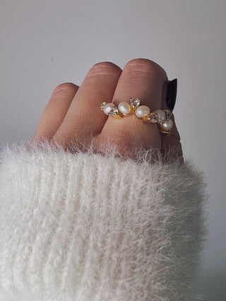 Freshwater Pearl Ring with pearls and cubic zirconia stones across a band ring in gold plating worn on a model with black pointed nails wearing a white knitted jumper from Zara - Gold Lunar
