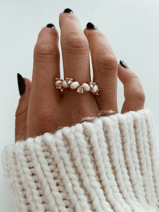 Freshwater Pearl Ring with pearls and cubic zirconia stones across a band ring in gold plating worn on a model with black pointed nails wearing a white knitted jumper from Zara - Gold Lunar