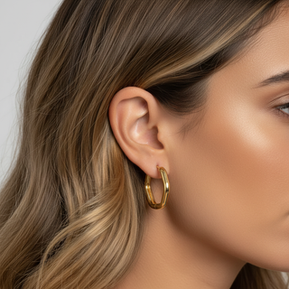 Close-up of a woman wearing a gold hoop earring with a neutral background