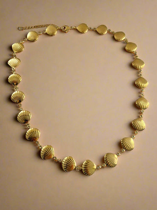 Gold necklace with shell-like links on a white background