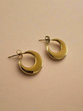 Gold hoop earrings on a beige background