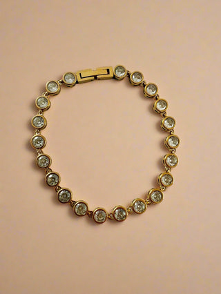 Gold bracelet with clear stones on a white background
