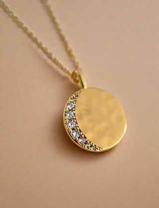 18k gold plated celestial moon disc with Cubic Zirconia stones in a crescent moon shape on a hammered molten disc on fine chain necklace
