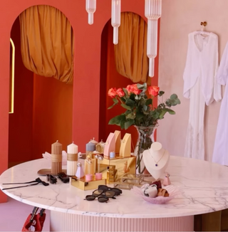 Table with beauty products and a vase of flowers against a red wall.