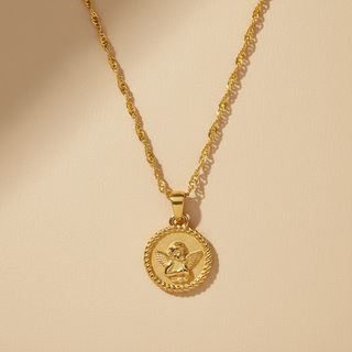 Gold necklace with an angel pendant on a beige background