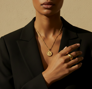 Woman wearing a black blazer and gold jewelry against a beige background