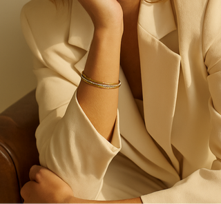 Woman in a beige suit sitting on a brown leather chair.