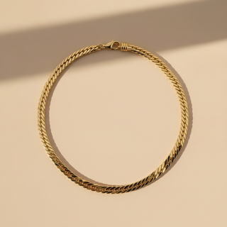 Gold chain necklace on a beige background