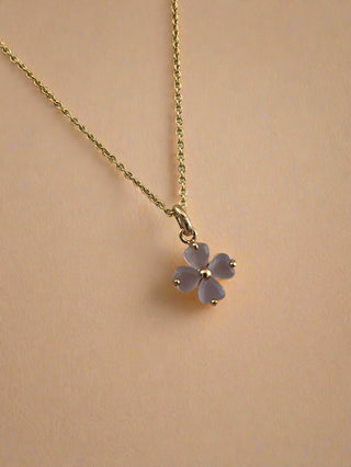 Gold necklace with a pink flower pendant on a light gray background