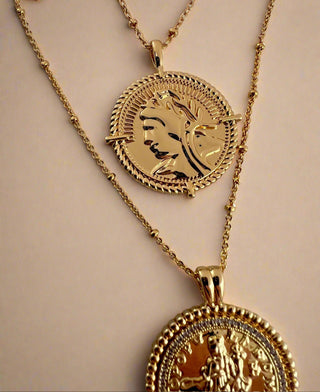 18k gold plated two coin necklaces one shorter than the other displayed on ceramic dish.