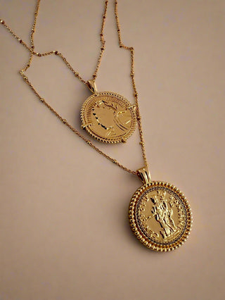 18k gold plated two coin necklaces one shorter than the other. displayed on ceramic dish.