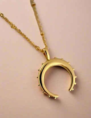 18k gold plated crescent moon necklace on fine ball chain on a jewellery dish