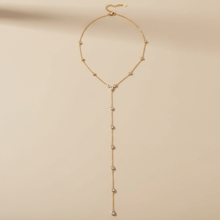 Gold necklace with beads on a beige background