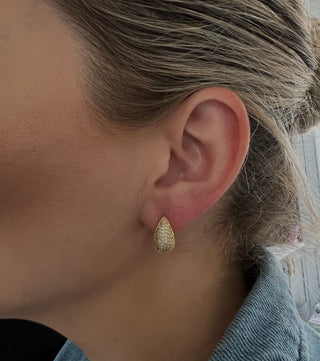 18k gold plated dome Teardrop shaped earrings embellished with  Cubic Zirconia stones worn on a model with hair tied back in a bun and wearing a Zara denim shirt - gold lunar