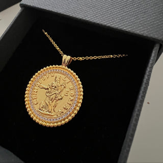 18k gold plated coin pendant necklace with cubic zirconia gemstones around the outside on a fine gold chain displayed inside a gold lunar gift box which is black with a velvet insert and gold branding on the front of the gift box