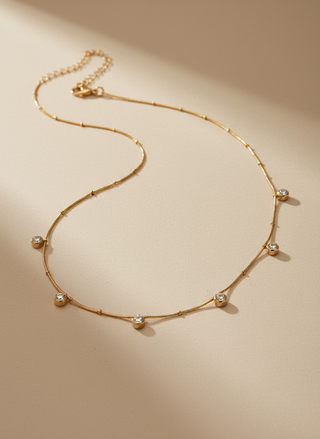 Gold necklace with small diamonds on a beige background