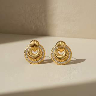 Pair of gold earrings with circular design on a beige surface