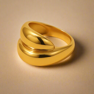 Gold ring with a smooth, curved design on a beige background