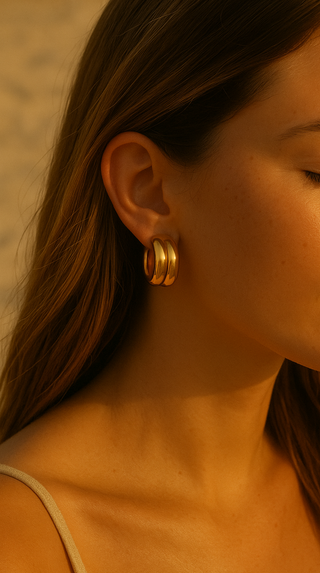 Close-up of a woman wearing gold hoop earrings with a warm, soft focus background.
