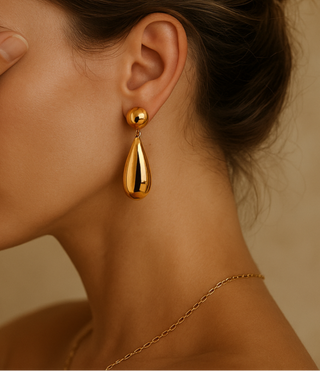 Woman wearing gold earrings with a neutral background