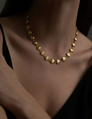 Gold necklace on a person against a dark background