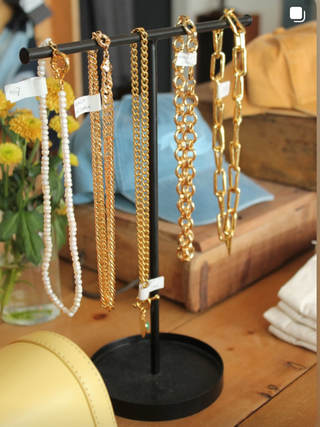 Gold chain necklaces on a black stand with a blurred background