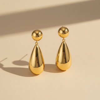Gold teardrop earrings on a beige background