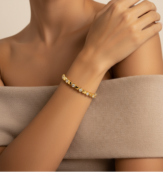 Gold bracelet with small stones on a wrist against a neutral background