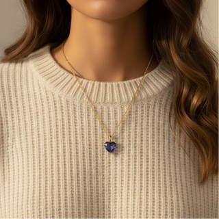 Woman wearing a necklace with a heart-shaped pendant against a neutral background