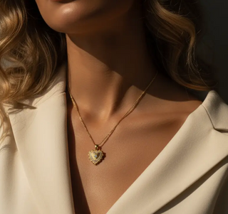 Close-up of a person wearing a gold necklace with a heart-shaped pendant.