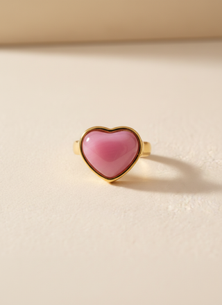 Heart-shaped pink ring with gold frame on a beige background