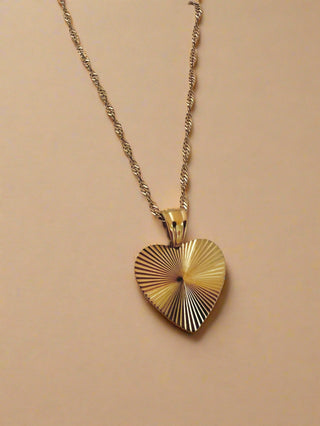 gold heart pendant on a twist rope chain displayed on a white pretty jewellery dish