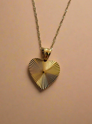 gold heart pendant on a twist rope chain displayed on a white pretty jewellery dish