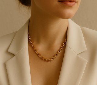 Woman wearing a gold chain necklace with a neutral background
