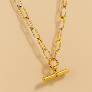 Gold chain necklace with a T bar pendant on a beige background