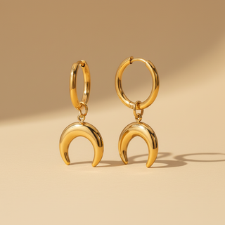 Gold hoop earrings with crescent moon pendants on a beige background