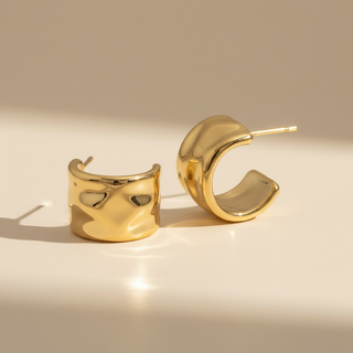 Gold hoop earrings on a beige background