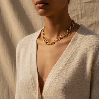 Close-up of a person wearing a gold chain necklace with a neutral background