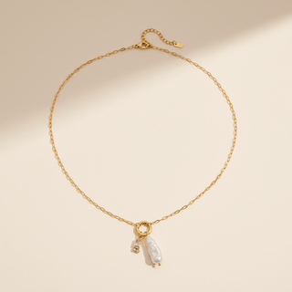 Gold necklace with a pearl pendant on a beige background