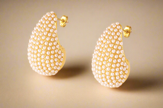 Gold earrings with pearl-like beads on a light background