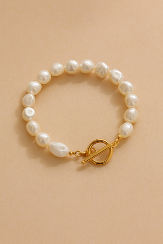 Pearl bracelet with a gold clasp on a beige background
