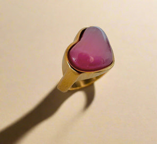 pink cats eye puffy heart ring in gold displayed on a white jewellery dish
