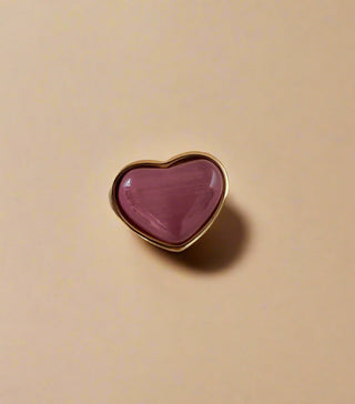 pink cats eye puffy heart ring in gold displayed on a white jewellery dish