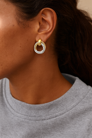 Close-up of a person wearing a gold and silver hoop earring.