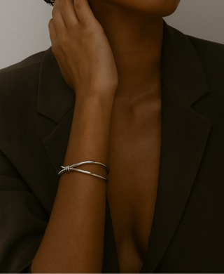 Woman wearing a silver bracelet and gold earring against a neutral background