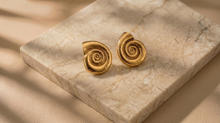 Gold spiral earrings on a marble surface