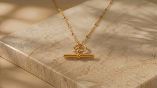 Gold necklace with a clasp on a marble surface