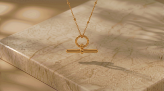 Gold necklace with a unique pendant on a marble surface